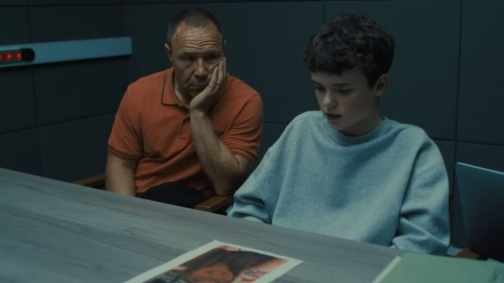 A still from Netflix's show Adolescence showing a father sitting in a police interrogation room with his 13-year-old son
